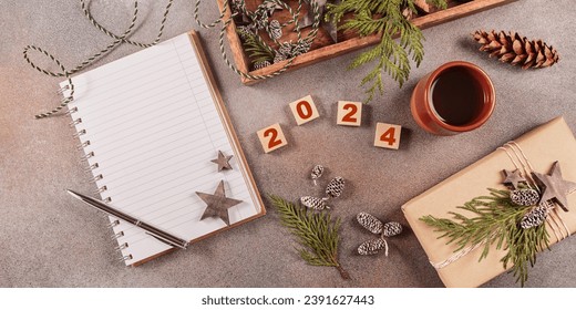 Winter holiday mood, Christmas, New Year background. Preparation for holidays. Notebook with pen, handmade gift box, Christmas wooden decor and numbers 2024. Flat lay, top view - Powered by Shutterstock