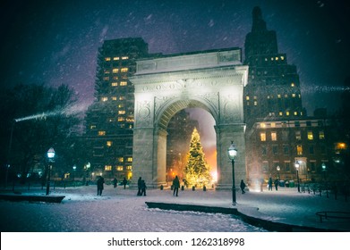 Winter Holiday Night View Of The Washington Square Park With A Christmas Tree Under Falling Snow In New York City