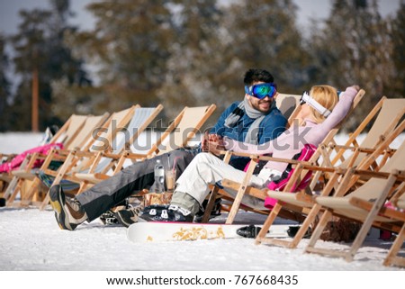 Winter holiday, ski, travel â?? smiling couple relaxing together in sun at mountains 