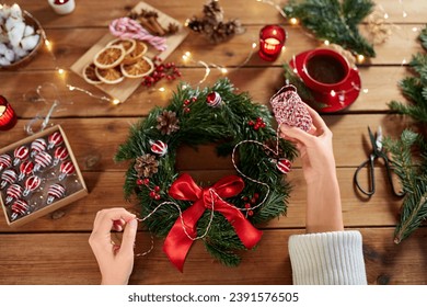 winter holidays, diy and hobby concept - close up of woman with decorative rope making christmas wreath at home - Powered by Shutterstock