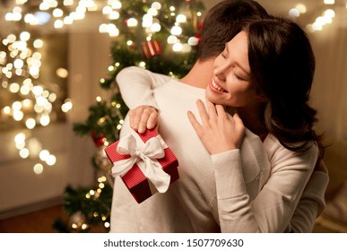 winter holidays and people concept - happy couple with christmas gift hugging at home - Powered by Shutterstock