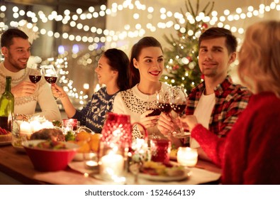 Winter Holidays And People Concept - Happy Friends Celebrating Christmas At Home Feast And Drinking Red Wine