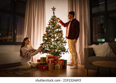 winter holidays and people concept - happy couple decorating christmas tree at home - Powered by Shutterstock