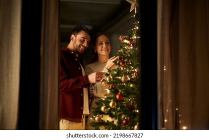 winter holidays and people concept - happy couple decorating christmas tree at home - Powered by Shutterstock