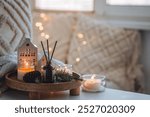 Winter home aromatherapy. Scented aroma candles, fir tree or spruce scent, decorative pine cones on wooden tray. Cozy atmosphere, relaxation, festive mood, interior decor bedroom, living room