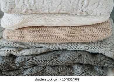 Winter home textile. Cozy warm knitted blanket and soft pillow stack.