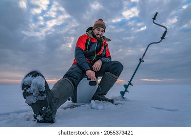 Winter ice fishing. Fisherman on lake catc fish from snowy ice - Powered by Shutterstock