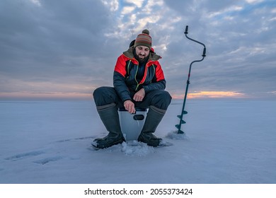 Winter ice fishing. Fisherman on lake catc fish from snowy ice - Powered by Shutterstock