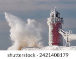 Winter, iced, South Haven, Michigan Lighthouse with splashing wave, Lake Michigan, USA