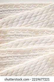 Winter Inspired Background Texture Image Of A White Cable Knit Scarf Laid Out In A Diagonal Pattern Descending Down The Length Of The Photo.
