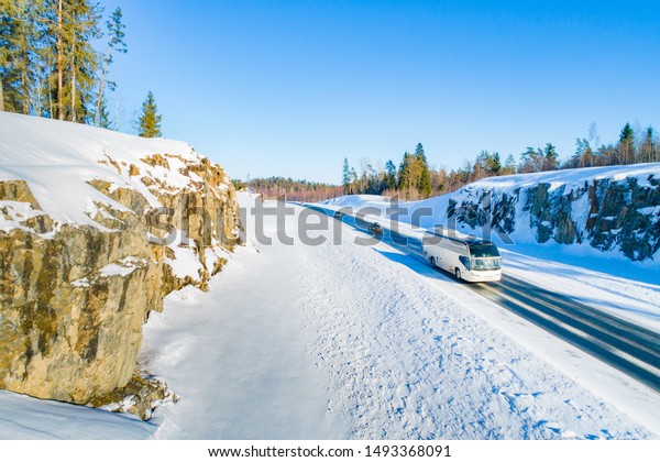 Winter journey. Bus\
transportation on the winter road. Road safety. Bus on the road.\
Snow-covered rocks and pines across the road. Trip to Karelia. Stay\
in the fresh air.