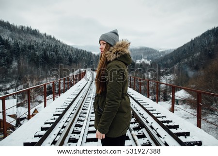 Winter journey. Girl in winter clothes on railway bridge in winter day.
