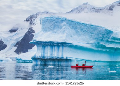 winter kayaking in Antarctica, extreme sport adventure, people paddling on kayak near iceberg - Powered by Shutterstock