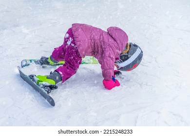 Winter, kid snowboarder on the ski slope in bright pink jacket.