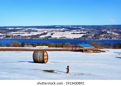 Winter Lakeshore Landscape Along Seneca Lake, In The Heart Of Finger Lakes Wine Country, New York. Seneca Lake Is The Deepest Lake Entirely Within The State. Wooden Wine Barrel On The Snow Ground 