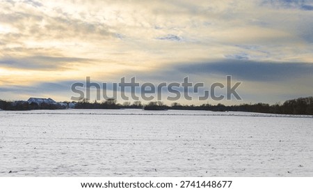 Winter landscape with bizarre clouds over snowed field
