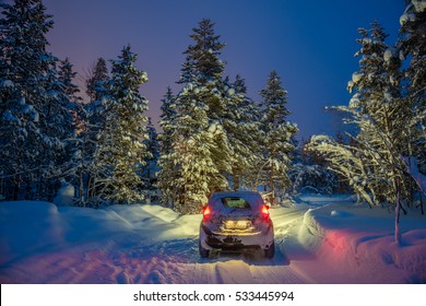 Winter Landscape With Car - Driving At Night - Lights Of Car And Winter Snowy Road In Dark Forest, Big Fir Trees Covered Snow