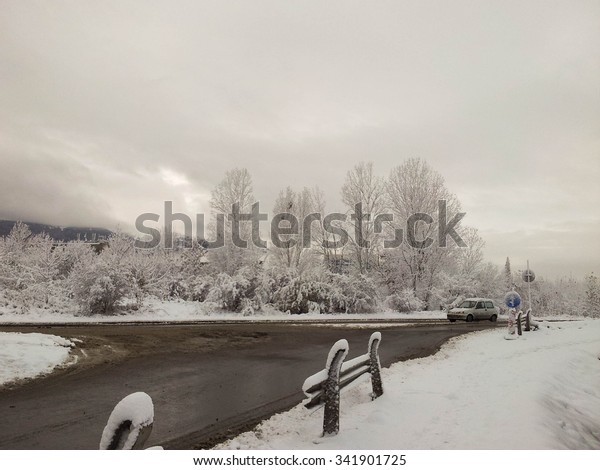 Winter\
landscape of a crossroad with a car on the right \
