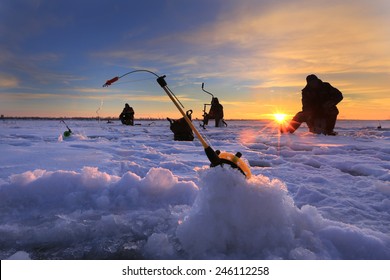 winter landscape fishermen on the ice of the river at sunset 