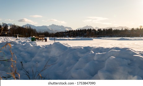 Winter Landscape Of Frozen Westchester Lagoon And The Mountains Of Chugach Park In The Back. Taken From Margaret Eagan Sullivan Playground. Near Downtown Anchorage, Alaska. Covered With Snow. Sunrise.