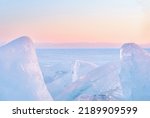 Winter landscape with ice hummocks glittering in the sun and mountains of Lake Baikal in Siberia at sunset. Natural background.