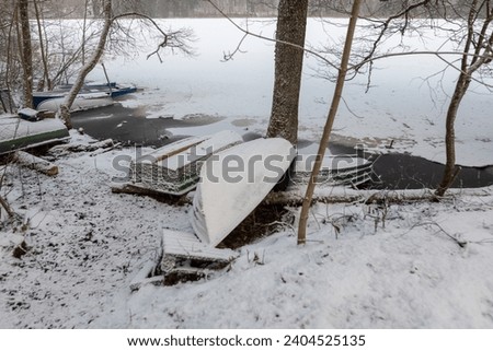 winter landscape with lake shore, flooded boats on lake shore, boat frozen in water, winter day