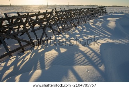 winter landscape. morning frost and sun. snow fence in the field 2022