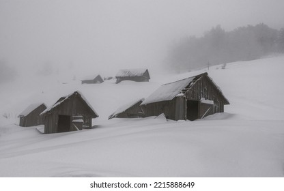 Winter landscape with old wooden huts. Abandoned cabins covered in snow. - Powered by Shutterstock