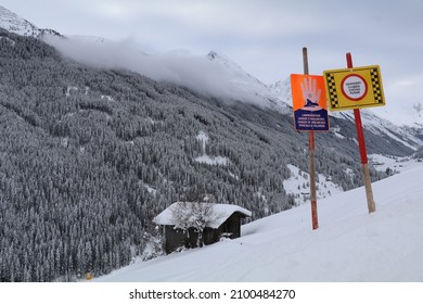 winter landscape with only color coming from signs warning for avalanges (signs read 'closed' and 'danger of avalanche') - Shutterstock ID 2100484270
