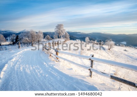 winter landscape. rural road covered with snow. mountains on horizon