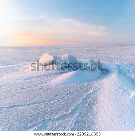Winter landscape. Snowdrifts on the ice surface during sunset.