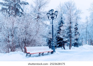 Winter landscape. Snowy trees along the winter park and a park bench covered with frost and snow. Winter wonderland scene - Powered by Shutterstock