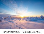 Winter landscape at sunset in Finnish Lapland. Cold winter with lot of snow and blue sky. Spruce trees covered by snow