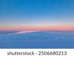 Winter landscape at sunset in Finnish Lapland. Cold winter with lot of snow and blue sky. Spruce trees covered by snow