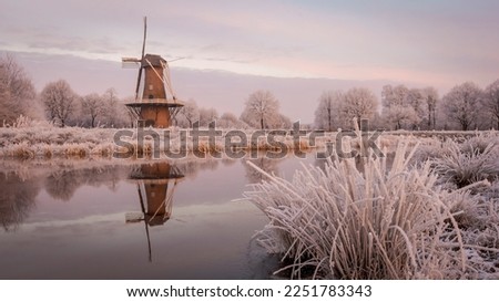Winter landscape with a traditional Dutch windmill along the Hunze river in the rural province of Drenthe, The Netherlands.