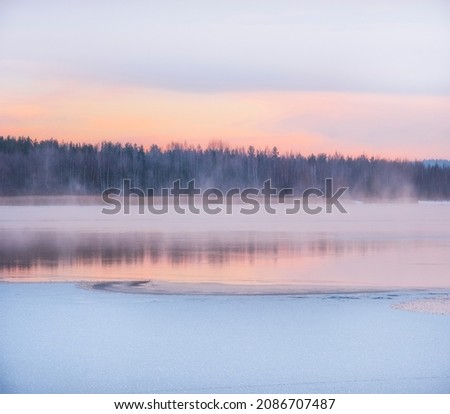 
Winter landscape, the water of the lake under the snow soars against the background of dawn and the forest.
