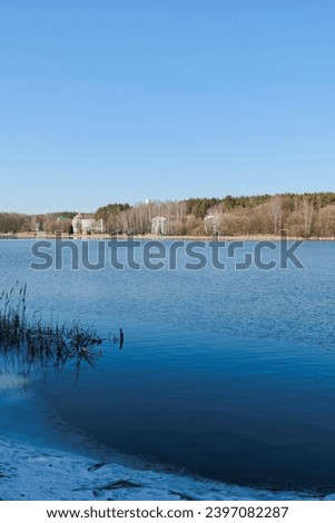 Winter landscape, white shore of a lake or river with snow and ice