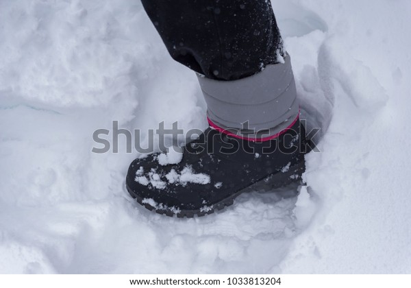 A\
winter landscape, a woman walking with boots on a snowy day, the\
road is overwhelmed with snow. Shallow depth of\
focus.