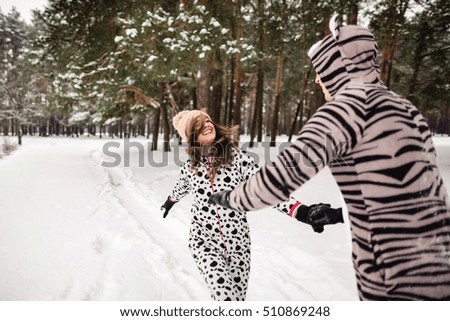 Winter love concept. Happy couple smiling and running in the winter forest in snowy weather