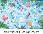 Winter  make up set on light blue background, with artificial snowflakes and Christmas tree branches. Various makeup professional cosmetics - shadows, lipstick, mascara, blush. Christmas beauty sale