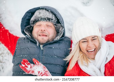 Winter, Middle Age Couple In Love. Woman And Man Lying Embracing Laughing On White Snow. Romantic Couple Have Winter Fun, Love Story Outdoors