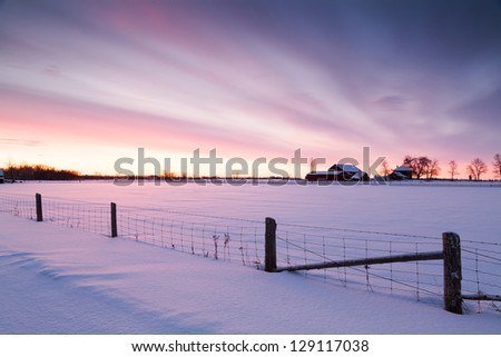 Winter morning landscape dramatic sky snow covered country field.