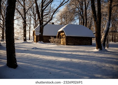 Winter morning landscape, early sun illuminates park area with vintage swing bench and old wooden buildings covered with snow. - Powered by Shutterstock