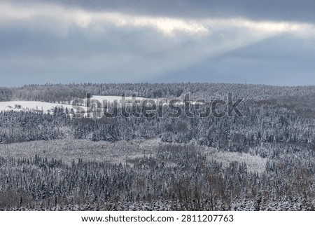 Winter Mountain Landscape with Sun Rays Shining Through the Sky A stunning winter mountain landscape illuminated by dramatic sun rays streaming through the clouds onto the snow-covered terrain. The combination of majestic mountains, pristine snow, and golden sunlight creates a peaceful and inspiring natural scene. Ideal for themes of winter, nature, travel, wilderness, outdoor adventure, and scenic backgrounds.