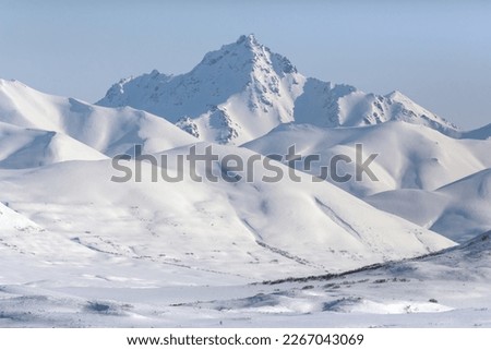 Winter mountain landscape. View of the snow-capped mountains. Majestic northern nature. Traveling and hiking in remote wilderness areas in the Arctic. Meingypilgyn Range, Chukotka, Far North of Russia