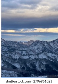 Winter Mountain Range Beneath Dramatic Clouds in Japan

A panoramic view of snow-covered mountains under dramatic winter clouds. Soft light breaks through the sky, creating a serene and atmospheric landscape in rural Japan.
