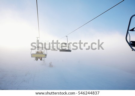 Winter mountains panorama with ski slopes and ski lifts, sunny day with fog and sun rays