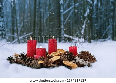 winter nature background with burning candles. candles, cones, dry orange slices in snow. magic winter scene in forest. Christmas, New Year Holidays. witchcraft ritual for Yule, Winter Solstice