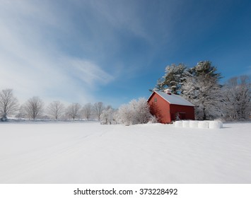 Winter In New England. Red Farm Building Contrasting With White Snow And Blue Sky. Ipswich, Massachusetts, USA 