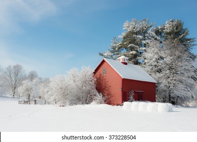 Winter In New England. Red Farm Building Contrasting With White Snow And Blue Sky. Ipswich, Massachusetts, USA 